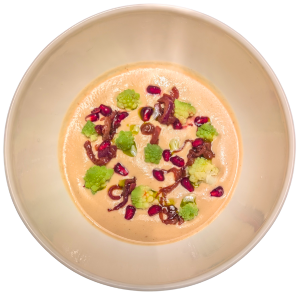Creamy soup of chickpeas and burnt corn, black garlic, cabbage vegetables, onion confit, and pomegranate