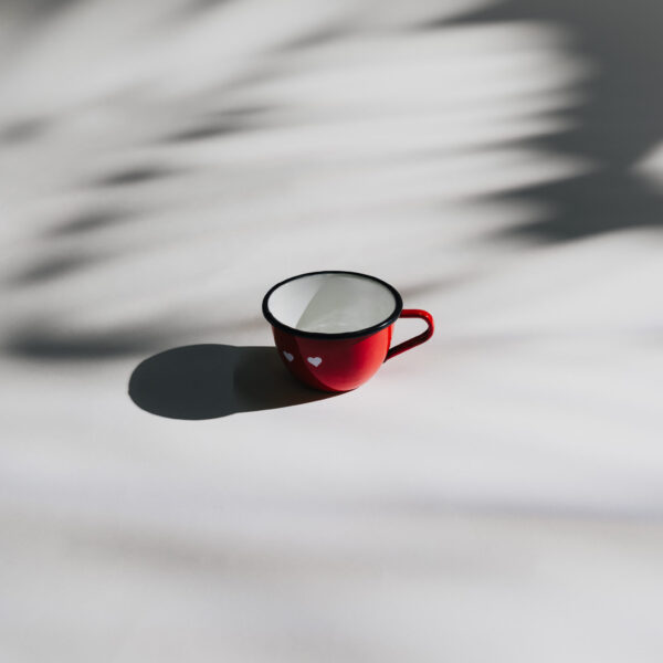 Red enamel mug with handle and heart pattern